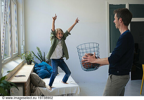 Cheerful boy winning and playing basketball with father at home