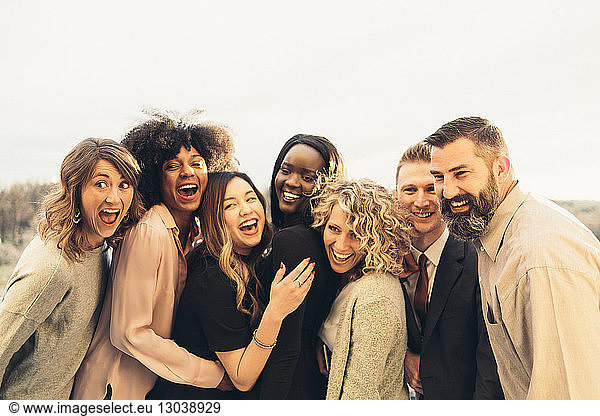 Cheerful business people looking away against clear sky