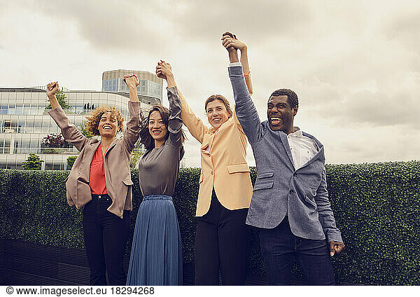 Cheerful businessman with colleagues celebrating on rooftop