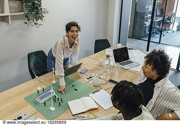 Cheerful businesswoman discussing over model with colleagues