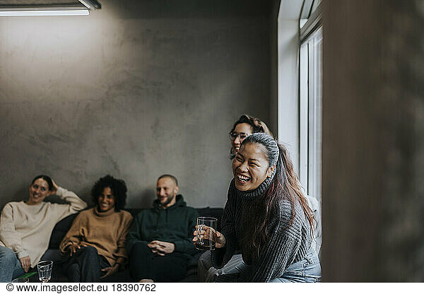 Cheerful businesswoman having coffee by colleagues while taking break in startup company