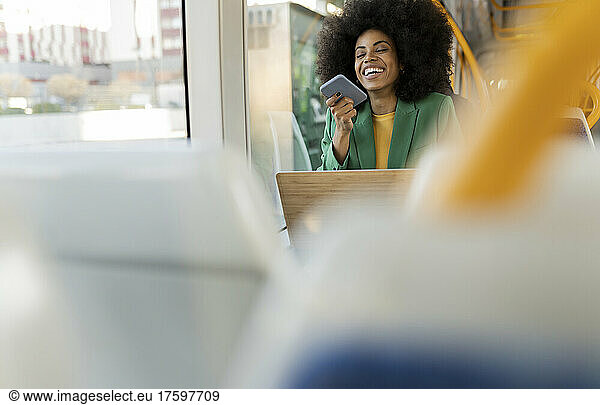 Cheerful businesswoman using mobile phone in tram