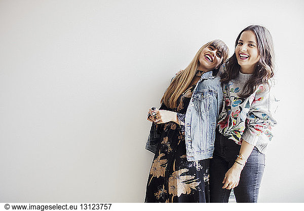 Cheerful businesswomen standing against white wall at office