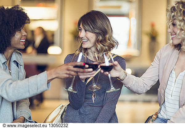 Cheerful businesswomen toasting wineglasses in hotel