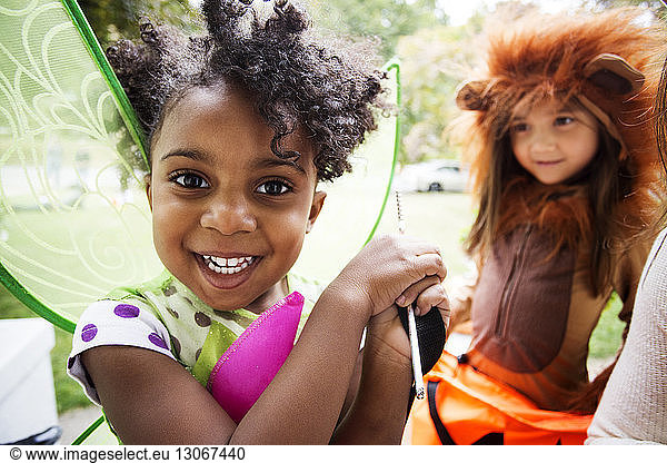 Cheerful children in Halloween costumes enjoying in yard
