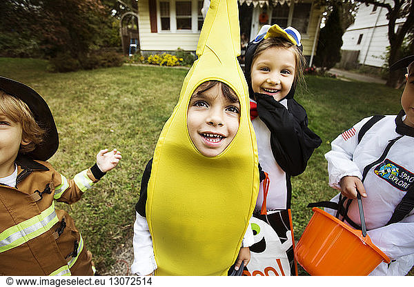 Cheerful children wearing Halloween costumes enjoying in yard during trick or treating