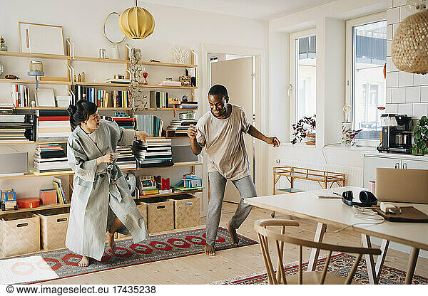 Cheerful couple dancing in living room at home
