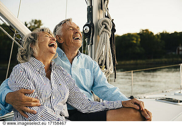Cheerful couple laughing while spending leisure time in sailboat