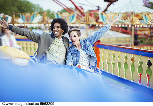Cheerful couple on carousel in amusement park