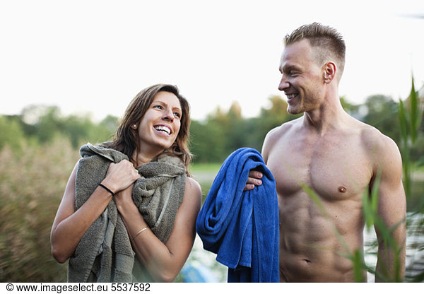 Cheerful couple with towel on beach