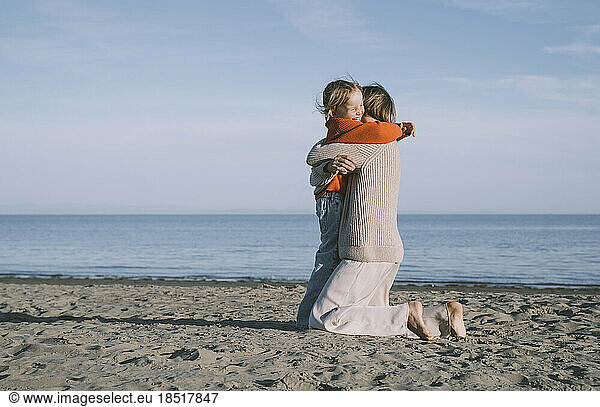 Cheerful daughter hugging mother at beach
