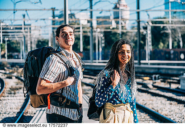 Cheerful diverse couple on railroad