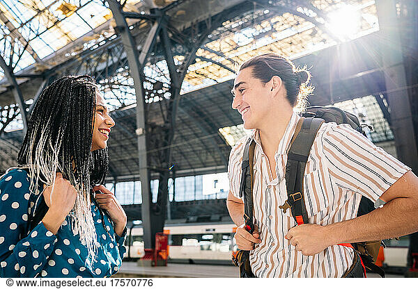 Cheerful diverse couple on railroad station