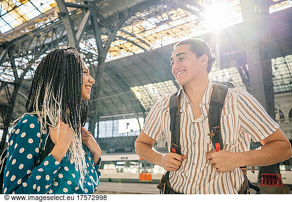 Cheerful diverse couple on railroad station