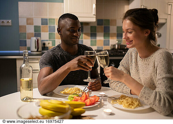 Cheerful diverse couple proposing toast during date