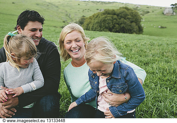 Cheerful family sitting on grassy field