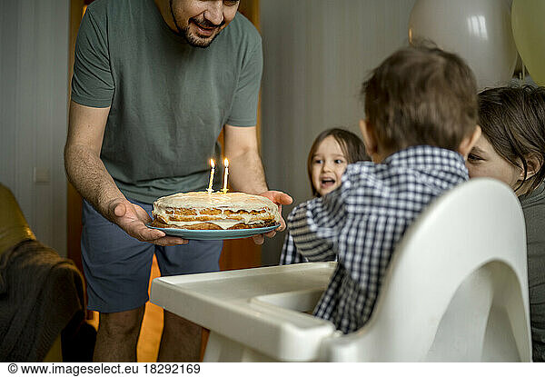 Cheerful family together celebrating son's birthday at home