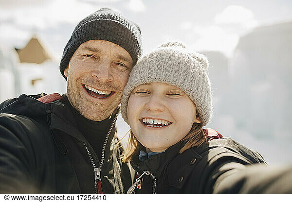 Cheerful father and daughter wearing knit hats during winter