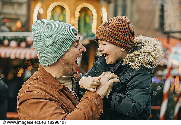 Cheerful father having fun with son at Christmas market