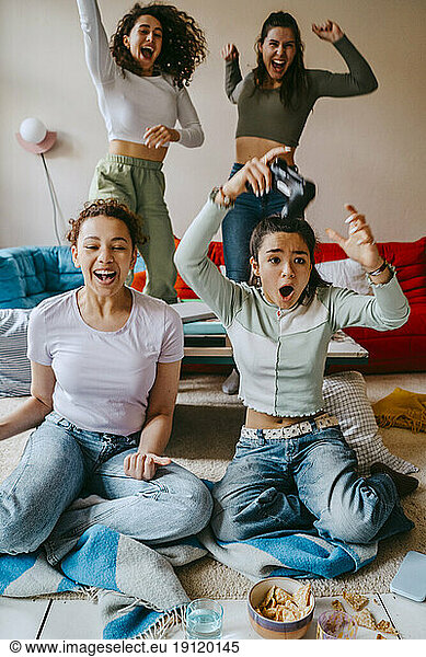 Cheerful female friends having fun playing video game at home