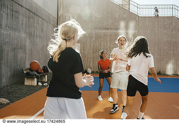 Cheerful female friends playing at basketball court