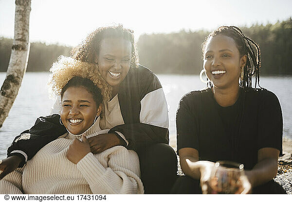 Cheerful female friends spending leisure time at lakeshore