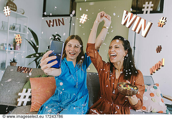 Cheerful female influencers advertising sweepstakes through mobile phone at home