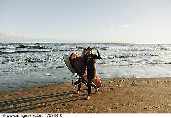 Cheerful female surfers with surfboards walking on sand at beach  Gran Canaria  Canary Islands