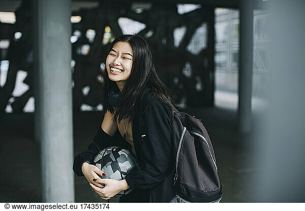 Cheerful female teenager laughing in parking garage