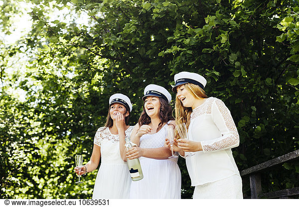 Cheerful female university students having champagne at graduation party