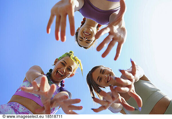 Cheerful friends gesturing together under sky
