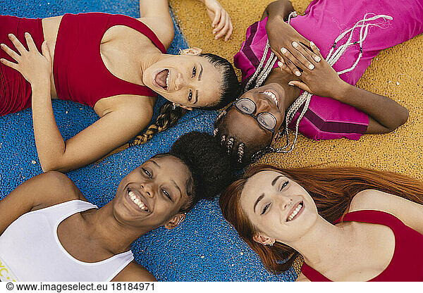 Cheerful friends lying down in sports court