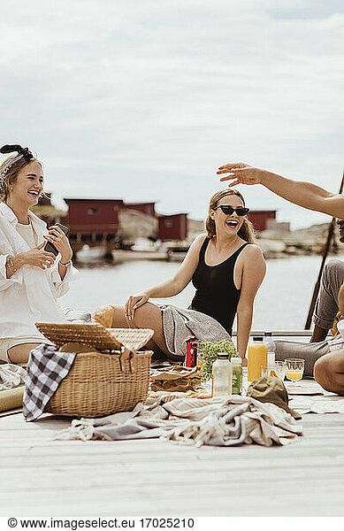Cheerful friends spending leisure time by sea at harbor