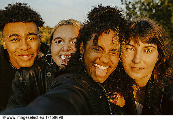 Cheerful friends taking selfie outdoors during sunset