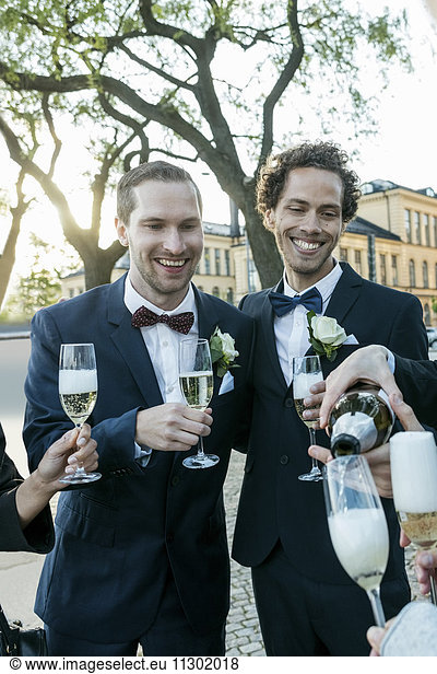 Cheerful friends with champagne during wedding ceremony