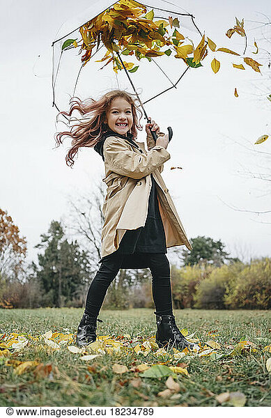 Cheerful girl having fun with umbrella in park