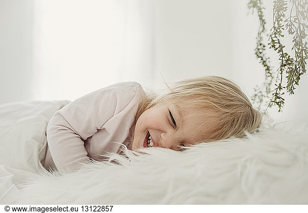 Cheerful girl lying on fur blanket at home