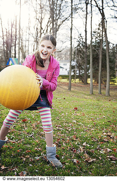 Cheerful girl playing with ball on field