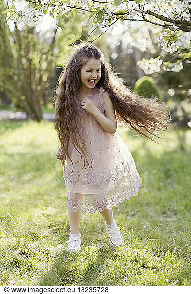 Cheerful girl running on grass in park