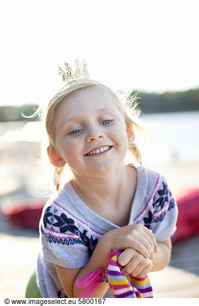 Cheerful girl wearing crown smiling outdoors
