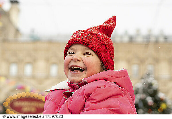 Cheerful girl wearing red knit hat enjoying at Christmas market