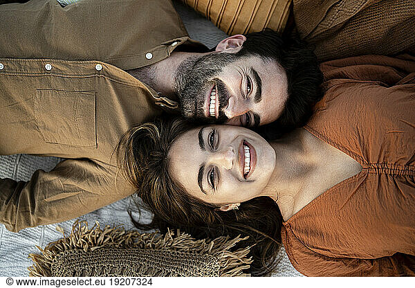 Cheerful girlfriend lying with boyfriend on picnic blanket