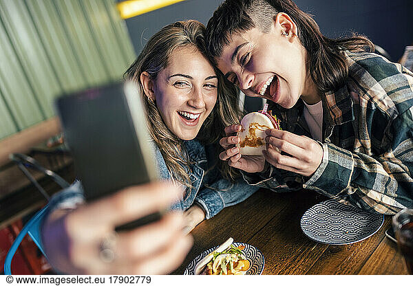 Cheerful lesbian couple taking selfie through smart phone