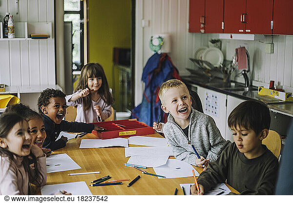 Cheerful male and female students enjoying while learning in kindergarten