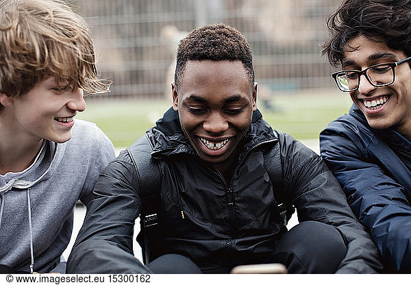 Cheerful male friends using social media after sports practice during winter