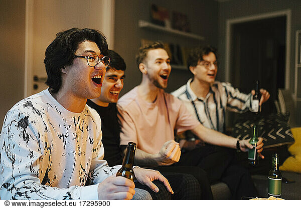Cheerful male friends watching sports together at home