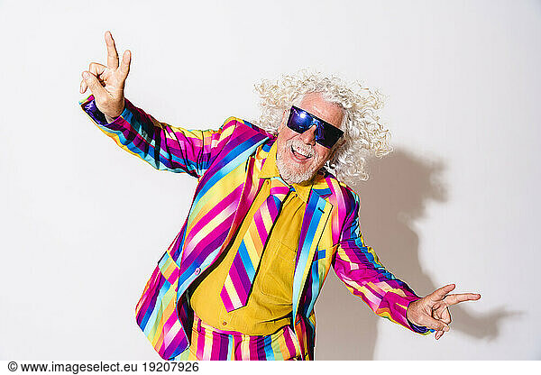 Cheerful man gesturing peace sign against white background