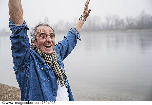 Cheerful man with arms raised enjoying at beach