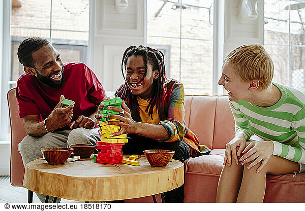 Cheerful man with friends playing block game at home