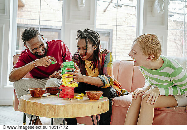 Cheerful man with friends playing block removal game at home
